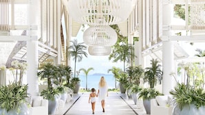 A spacious corridor with a high ceiling, large windows, and potted plants. - LUX* Grand Gaube (Grand Gaube)