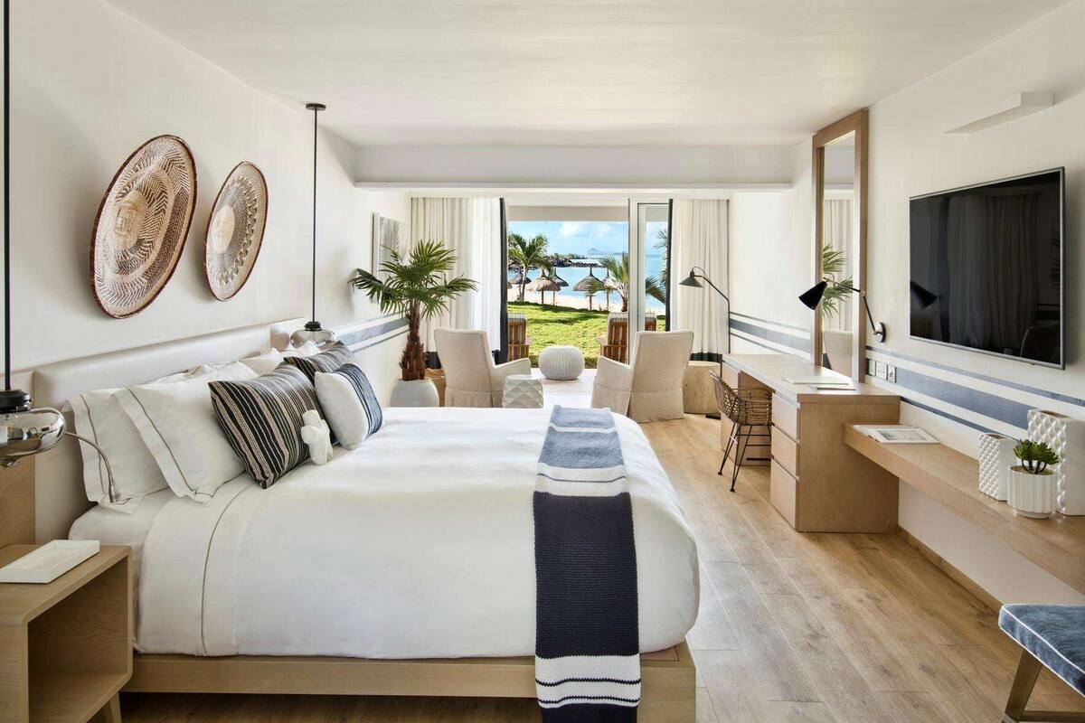 A modern hotel room with a large bed, a desk, and a TV.