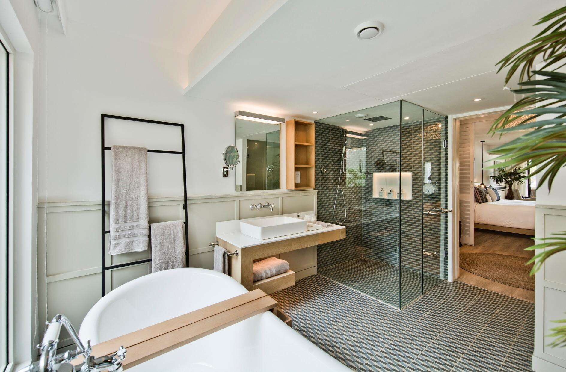 A modern bathroom with a freestanding bathtub, a glass-enclosed shower, and a vanity with a mirror.