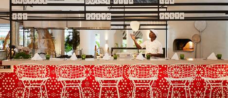 A restaurant with a bar area featuring a red and white patterned wall and white bar stools.
