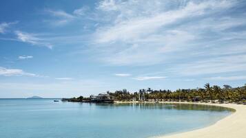 Na praia, espreguiçadeiras, guarda-sóis, toalhas de praia