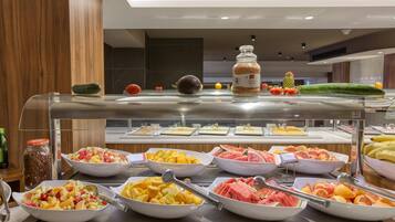 A buffet with various fruits and a jar of granola.