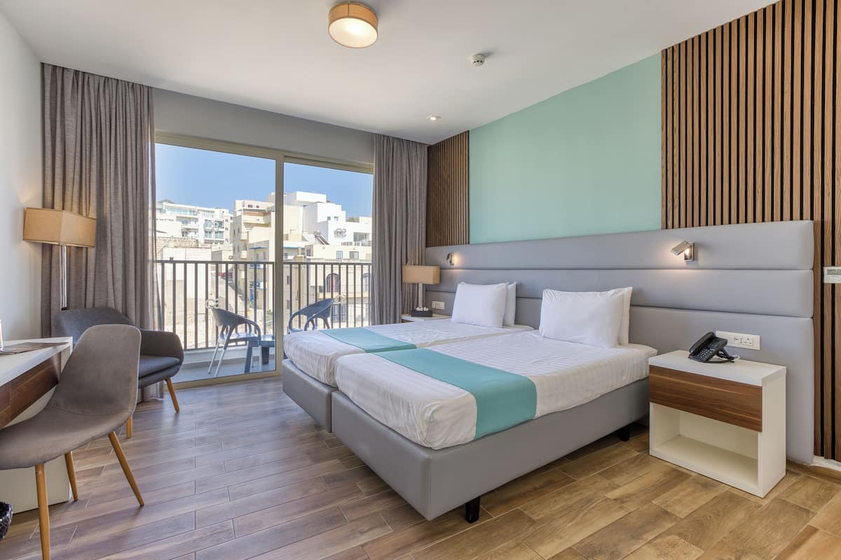 Quarto de hotel moderno com uma cama grande, uma escrivaninha e uma cadeira.