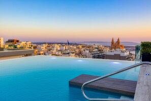 A rooftop infinity pool with a cityscape view, including a prominent church. - Solana Hotel & Spa (Mellieha)