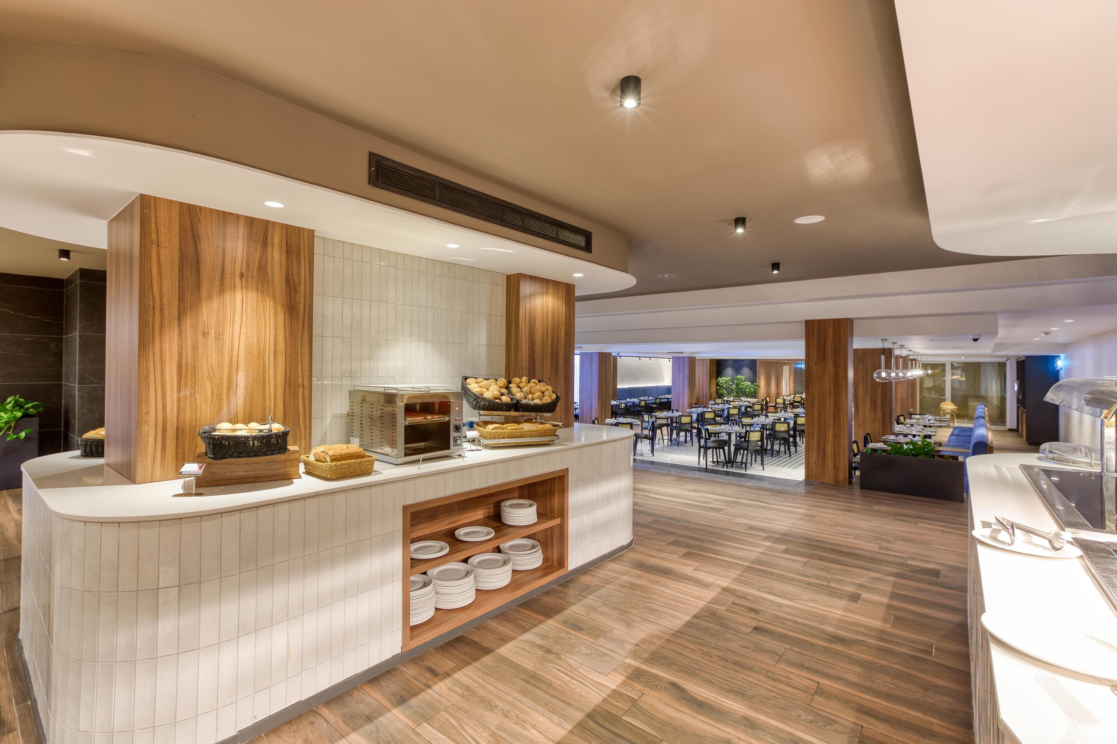 A modern hotel lobby with a reception desk, buffet area, and seating area.