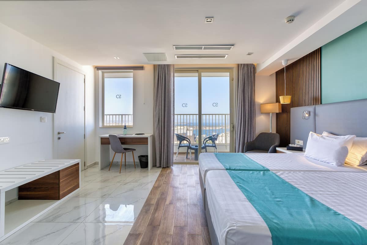 Quarto de hotel moderno com cama, escrivaninha e televisão.