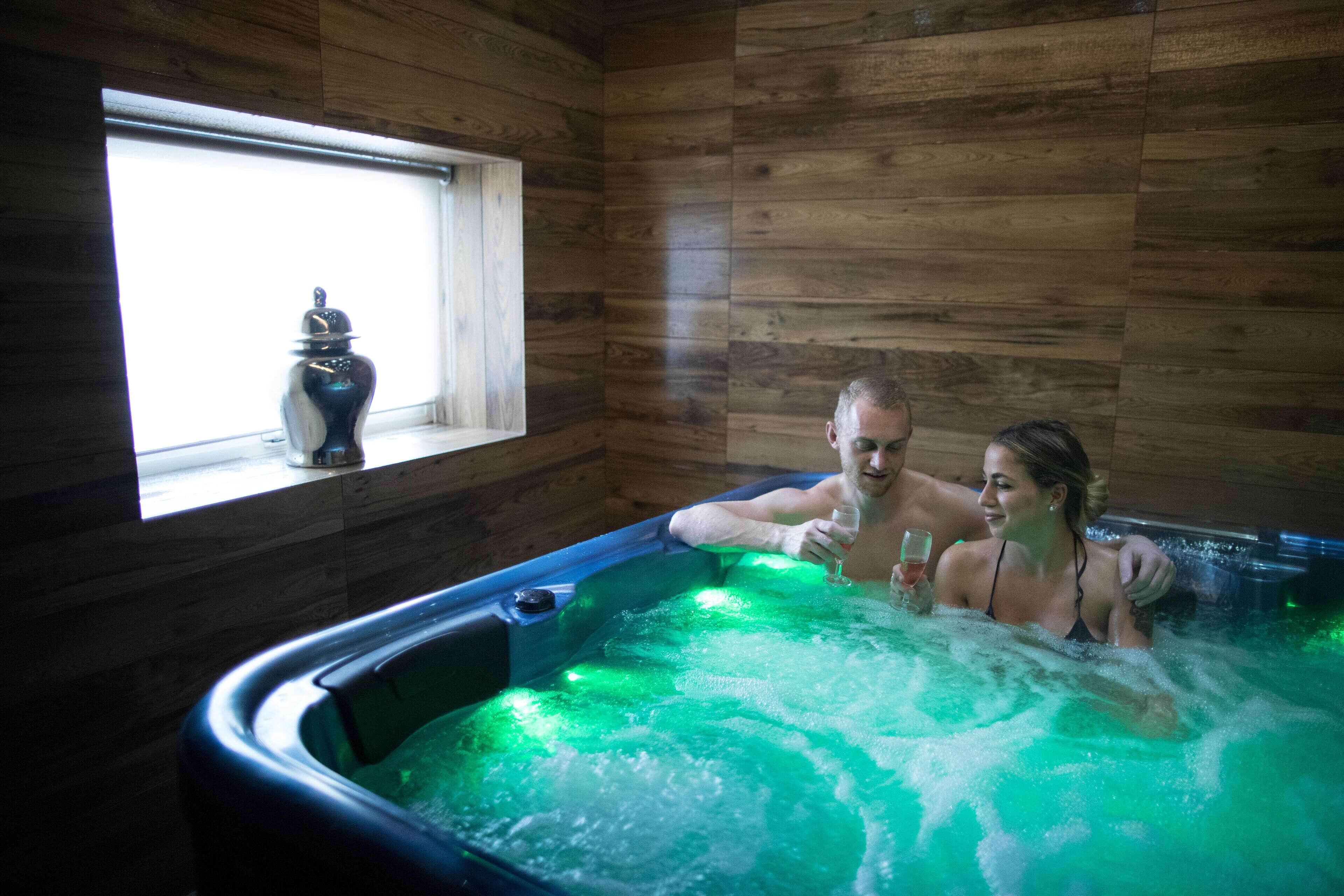 A wooden cabin interior with a hot tub, a window, and a decorative item on the windowsill.
