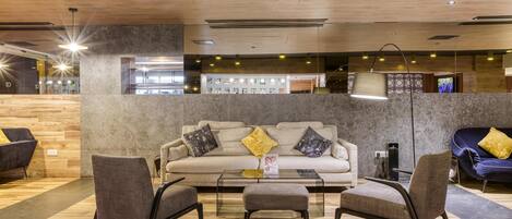 A modern lobby with a wooden ceiling, a sofa with cushions, and a glass coffee table.