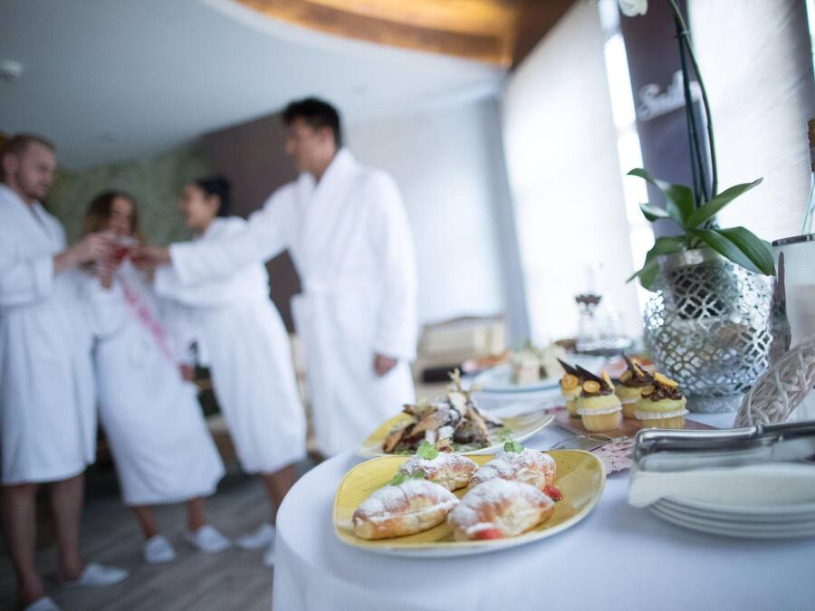 Un grupo de personas vestidas de blanco alrededor de una mesa con comida y bebidas.
