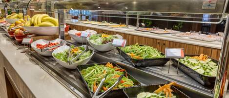A buffet with various food items including fruits, vegetables, and salads.