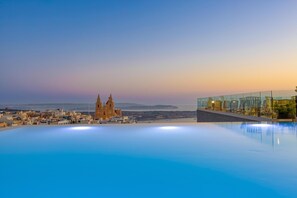 Una piscina con vista a un paisaje urbano, que incluye una iglesia destacada y edificios modernos.