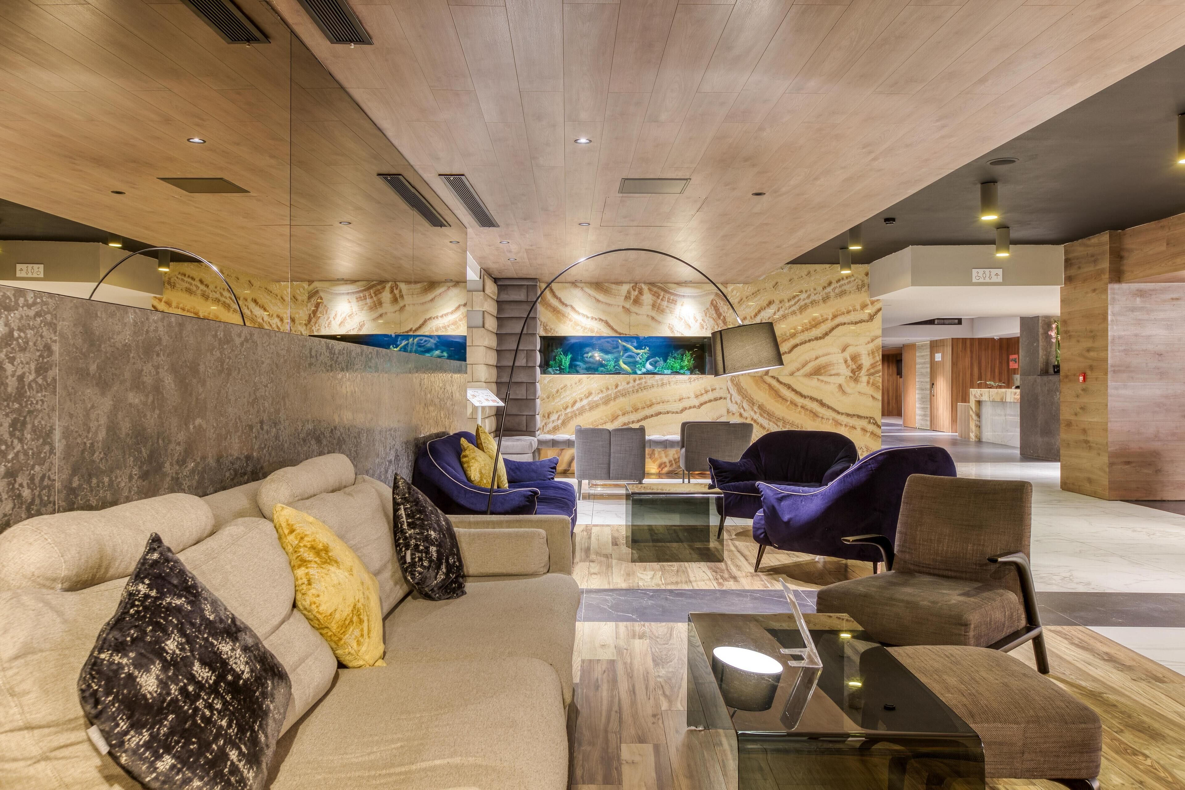 Un espace de détente moderne, avec des canapés, des fauteuils et une table basse en verre.