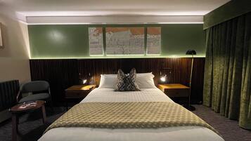 Habitación de hotel con una cama grande, dos mesitas de noche, una silla, un escritorio y un mapa en la pared.