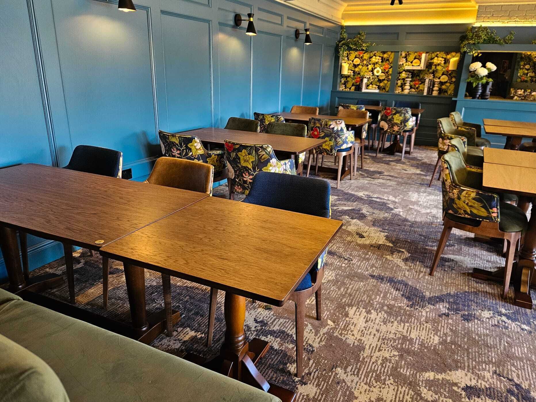 A restaurant with wooden tables and chairs, blue walls, and floral decorations.