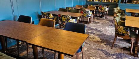 A restaurant with wooden tables and chairs, blue walls, and floral decorations.