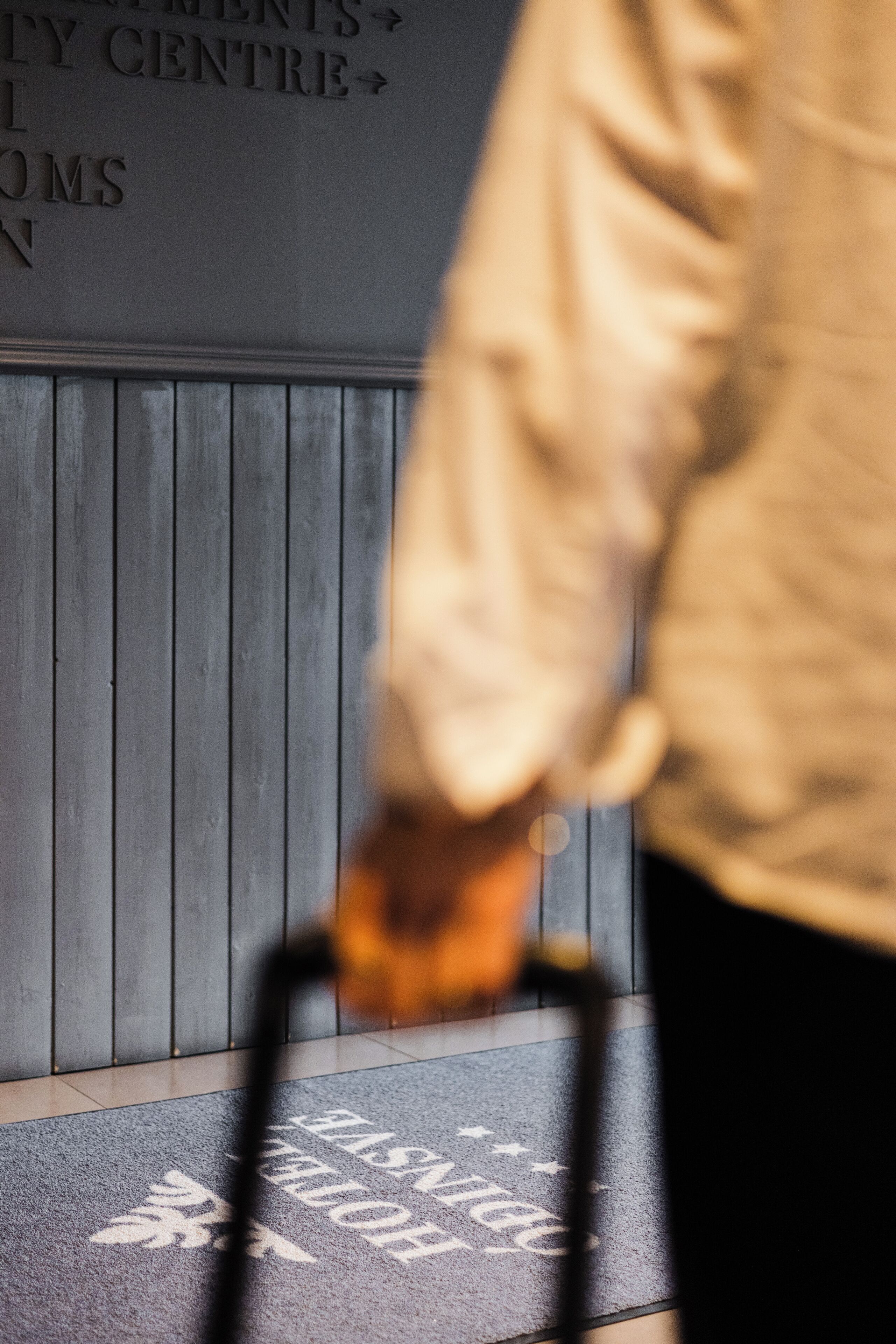 A person walking past a wall with a sign indicating directions to various facilities.
