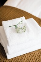 Una toalla blanca doblada con una ramita de follaje sobre una superficie marrón con textura.