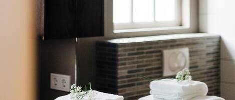 A bathroom with a mirror, a window, and a stack of white towels.