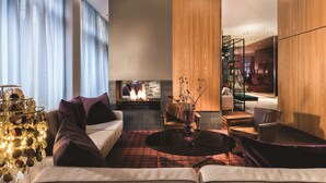 Una sala de estar moderna con chimenea, asientos cómodos y una lámpara decorativa.