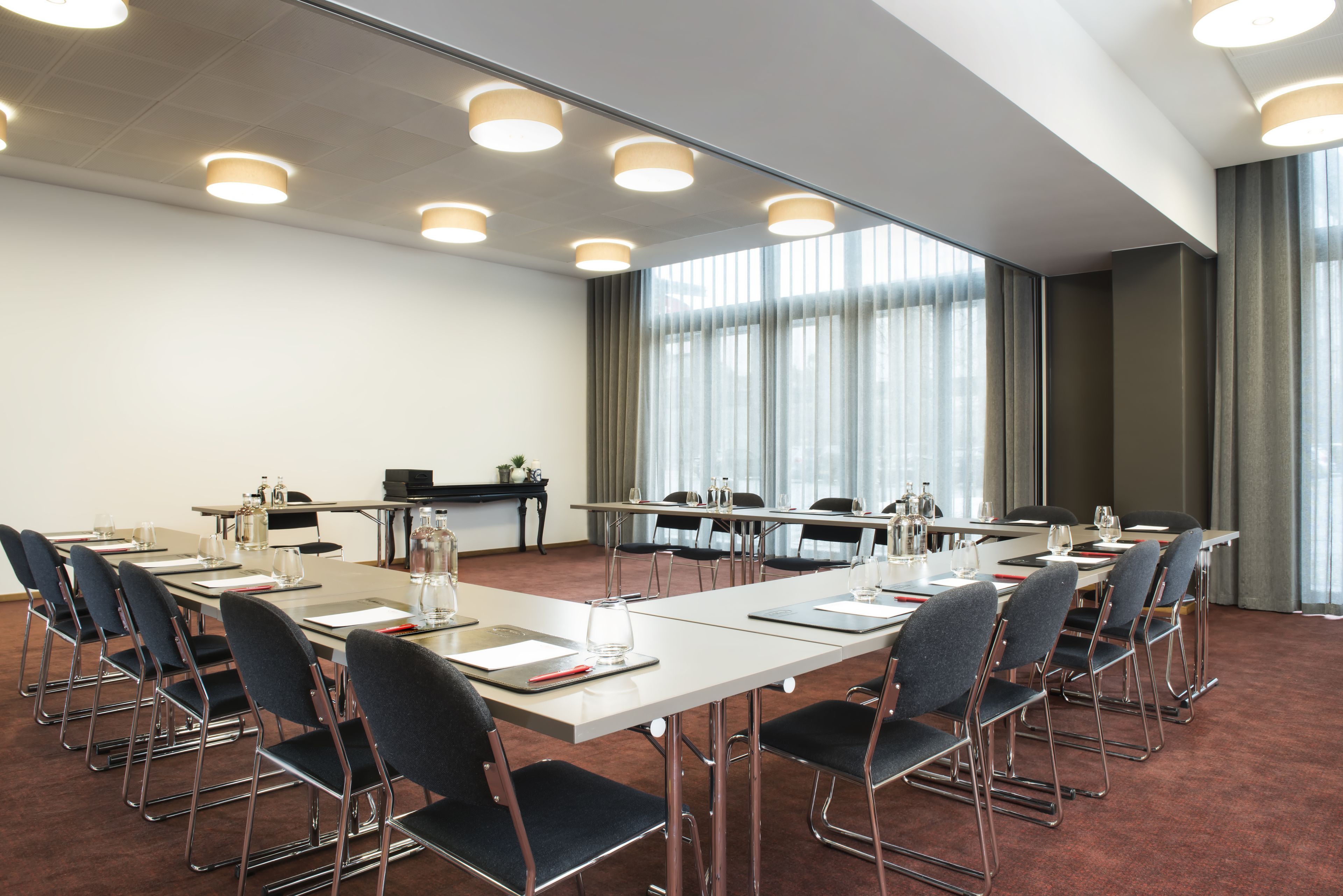 A conference room with a long table, chairs, and a projector screen.