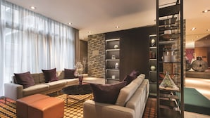 Una sala de estar moderna con un sofá, un reposapiés y una estantería.