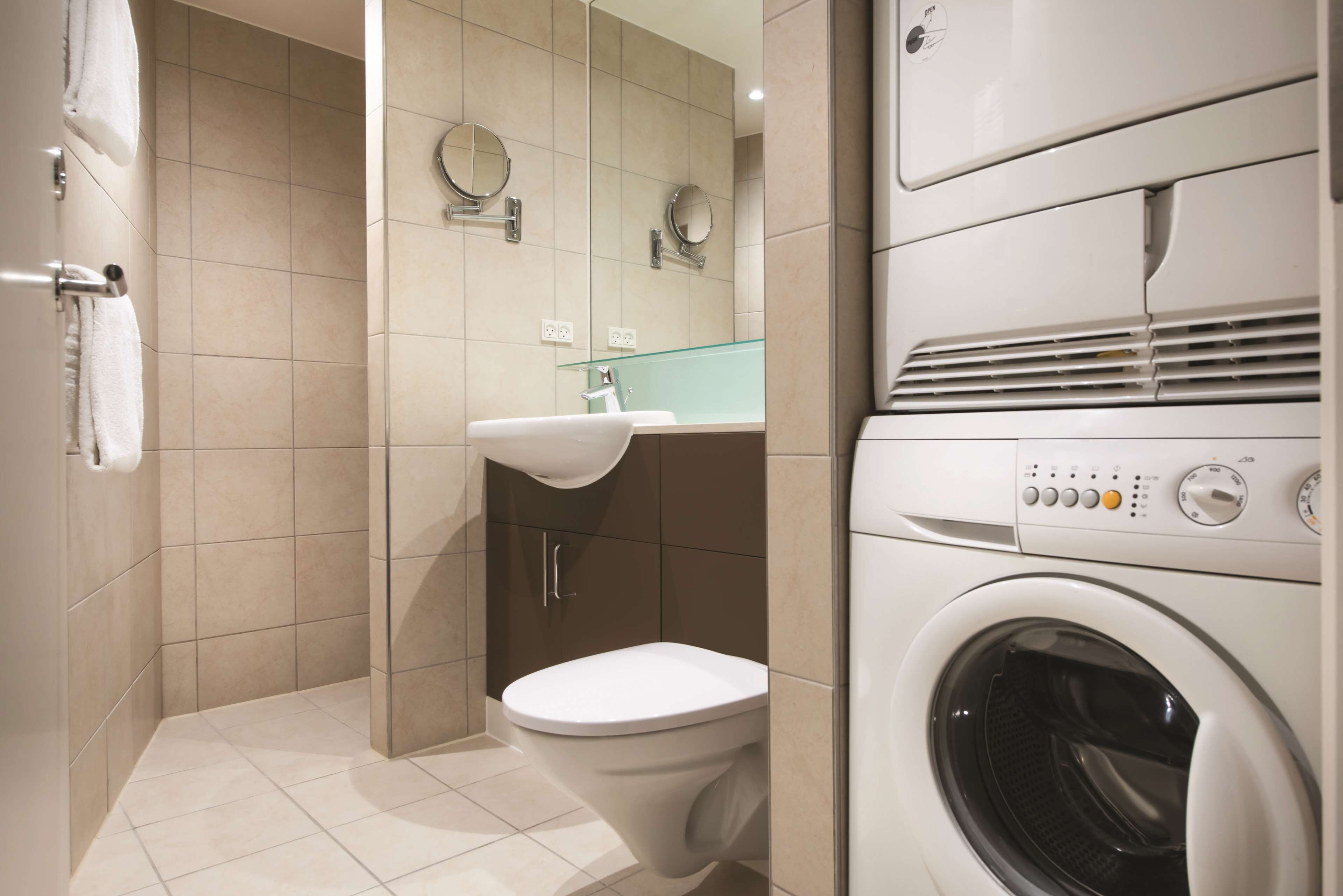 A modern bathroom with a toilet, sink, and stacked washer and dryer.
