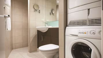 Un baño moderno con inodoro, lavamanos y lavadora y secadora apiladas.