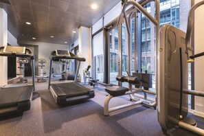 Une salle de sport équipée de tapis de course, d’un banc de développé couché et d’un support à squats.