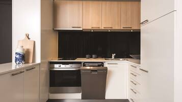 A modern kitchen with white cabinets, a stainless steel oven, and a dishwasher.