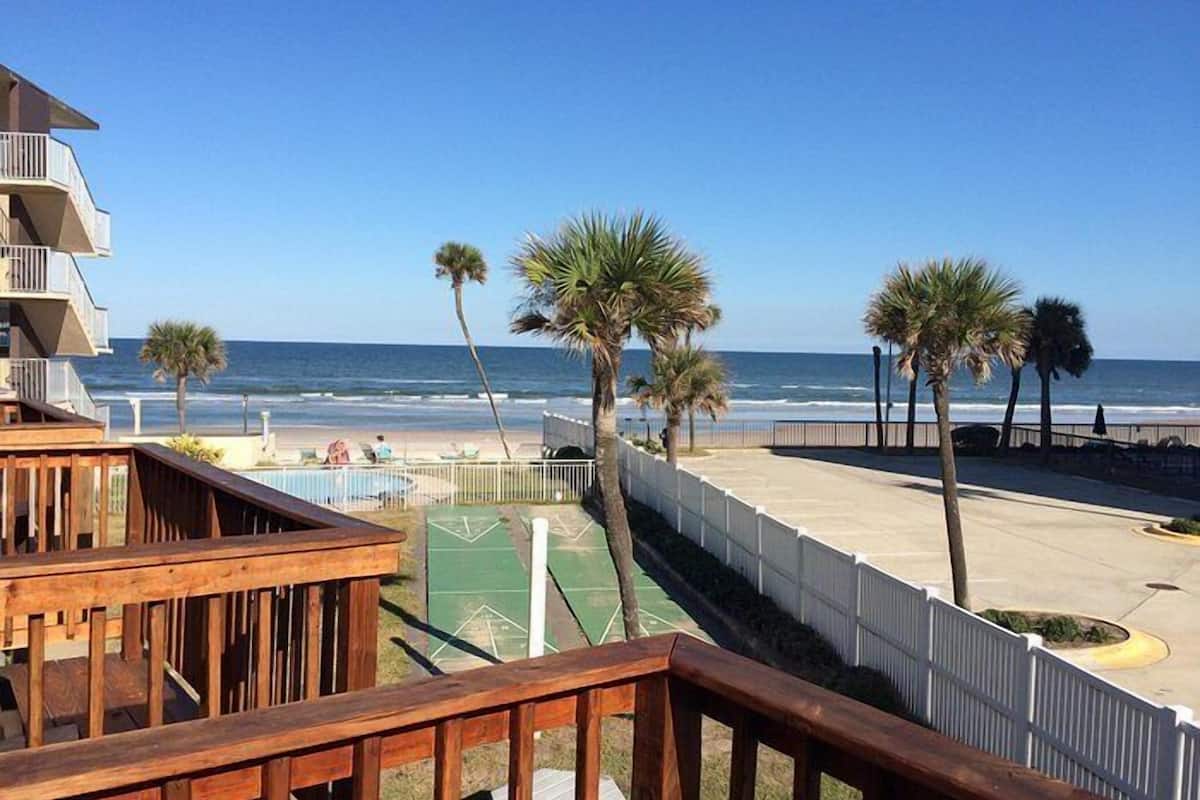 A beachfront property with a wooden deck, a pool, and a view of the ocean.