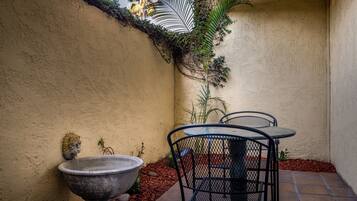A patio with a stone fountain, metal chairs, and a wall-mounted decorative element.