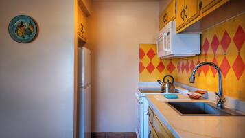 Una cocina compacta con microondas, pileta y un detalle decorativo en la pared.