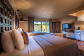 Une chambre d’hôtel avec deux lits, une télévision, une petite kitchenette et une vue sur l’extérieur.