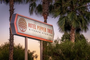 Une enseigne pour l’hôtel Pepper Tree Kitchen Studios, avec un logo représentant un arbre.