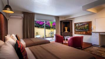A hotel room with two beds, a dining area, and a view of the garden.