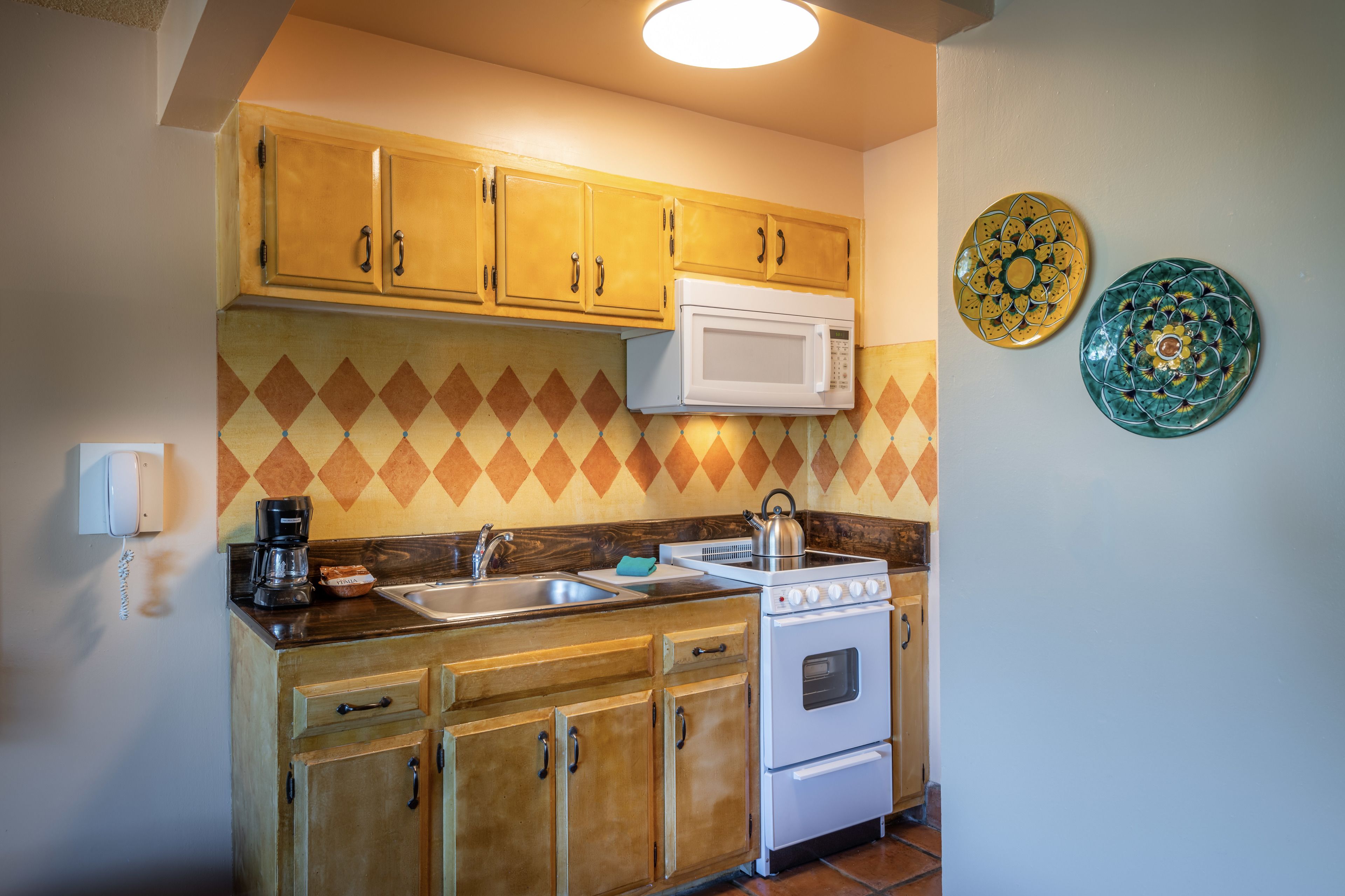 A kitchen with wooden cabinets, a microwave, an oven, a coffee maker, and a sink.