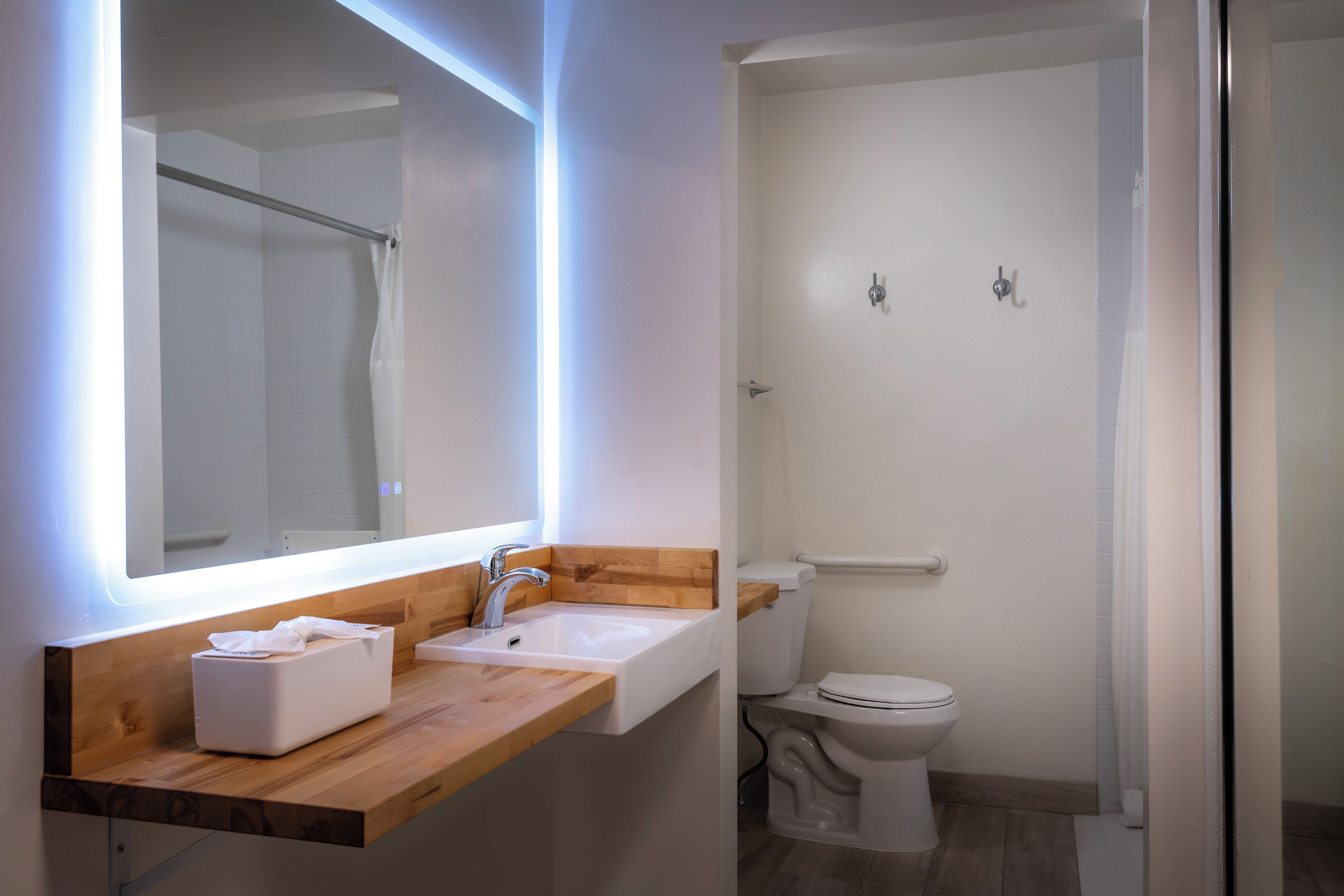 Une salle de bain moderne avec un meuble-lavabo en bois, un miroir, un lavabo et des toilettes.