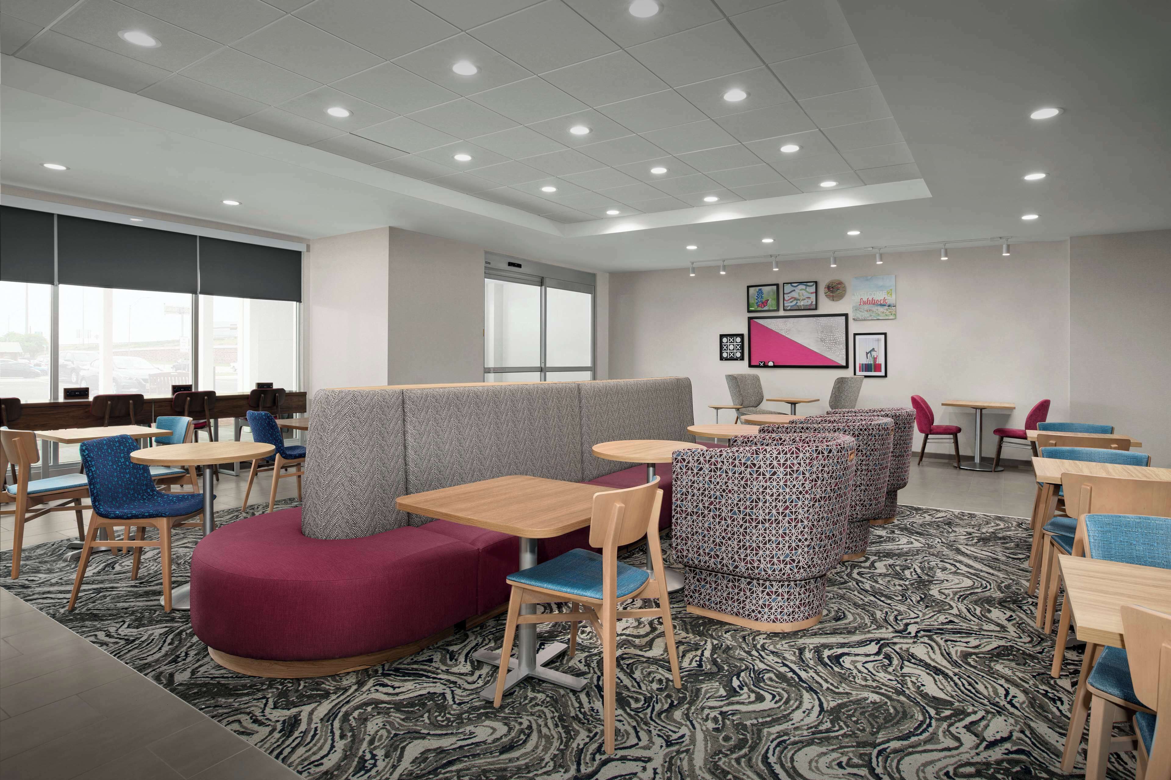 A modern lounge area with seating arrangements, tables, and artwork on the walls.