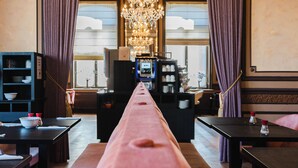 A hotel room with a long table, a chandelier, and a view of the outdoors. - Golden Tree Hotel (Bruges)