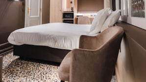 A hotel room with a bed, a chair, a TV mounted on the wall, a window with curtains, and a ceiling with a skylight. - Golden Tree Hotel (Bruges)