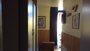 Un pasillo con un banco de madera, un radiador y una puerta que da a otra habitación.