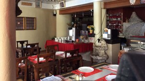 Un comedor con mesas dispuestas para cuatro, una escalera y una escultura de piedra.