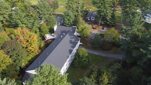 An aerial view of a residential area with a large house featuring a long, straight roofline, surrounded by dense trees and a well-maintained lawn. - Warren Conference Center and Inn (Ashland)