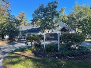 A hotel entrance with a sign reading "The Inn at Warren," surrounded by trees and a well-maintained lawn. - Warren Conference Center and Inn (Ashland)