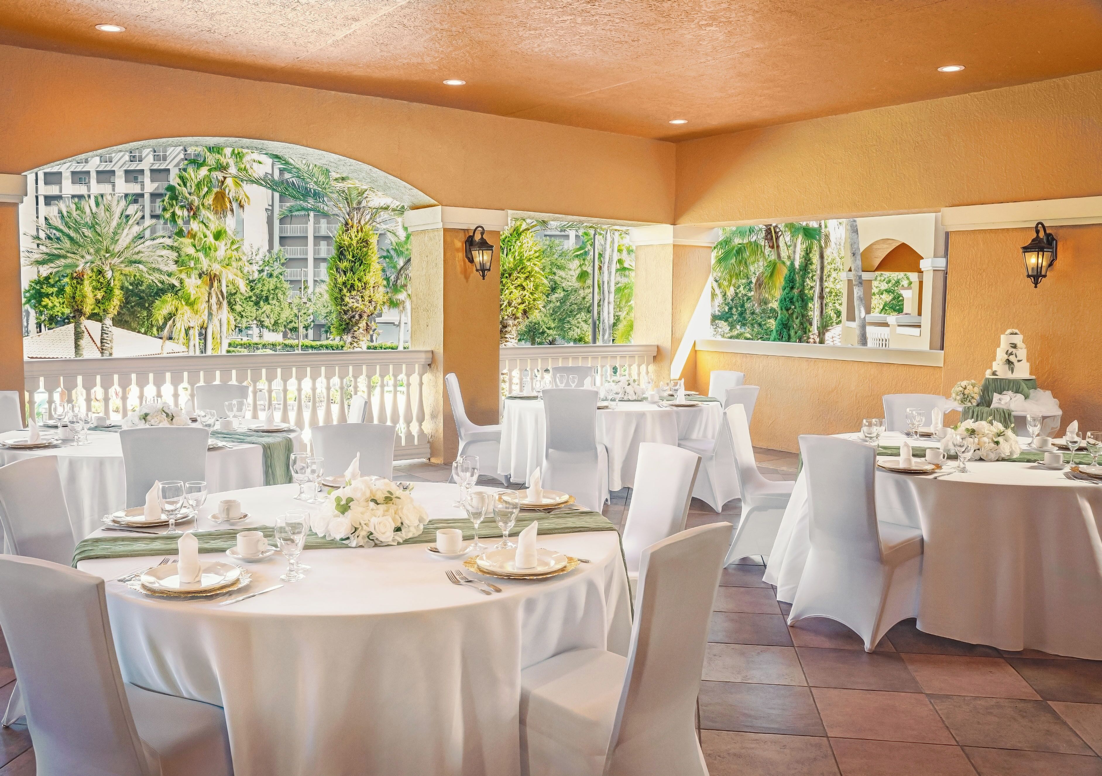 A banquet hall with round tables set for a formal event, featuring white tablecloths, chairs, and floral centerpieces.