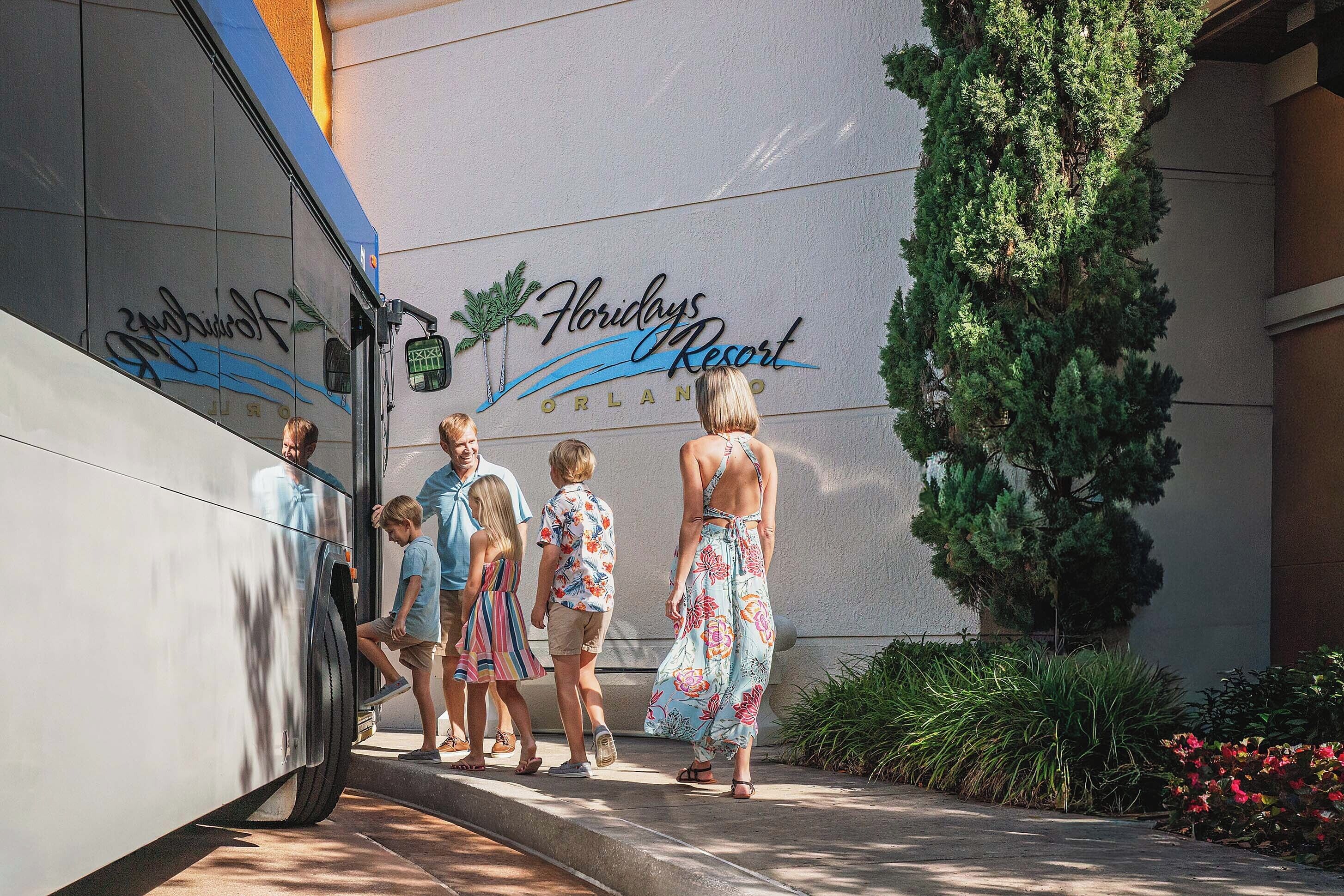 Un groupe de personnes monte à bord d’un autobus à l’entrée d’un hôtel appelé « Florida’s Resort Orlando ».
