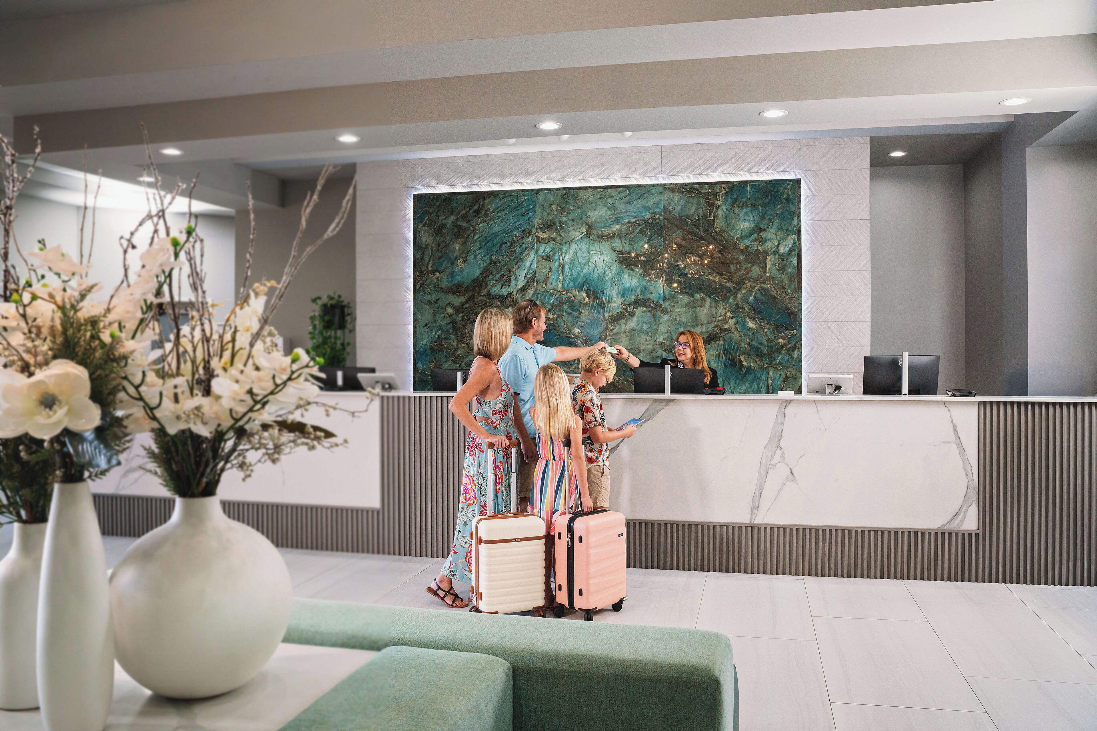 A reception area with a marble reception desk, a large abstract painting, and a green seating area.