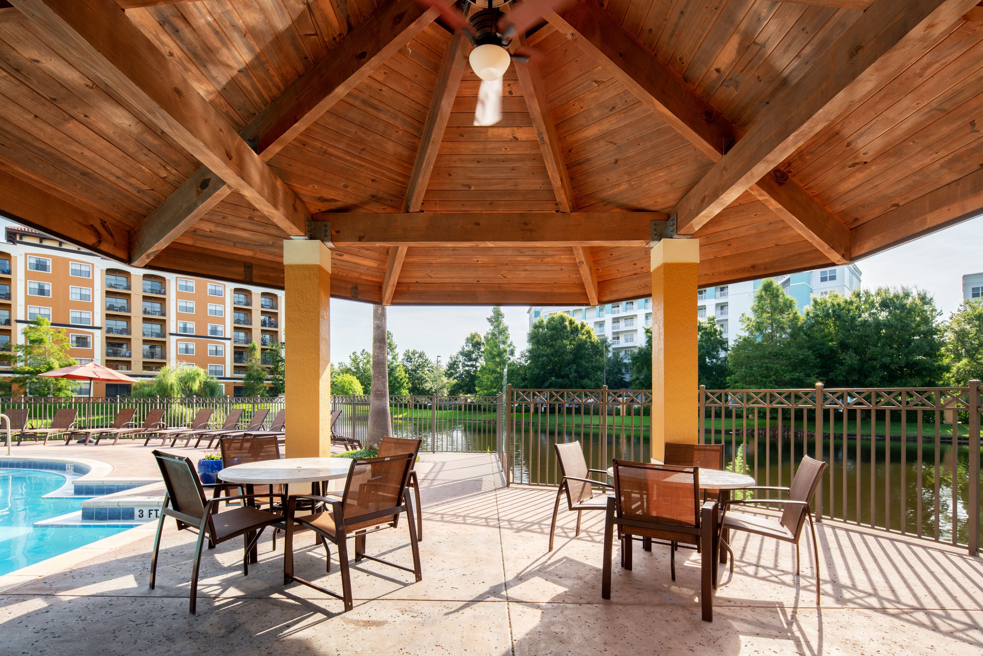 A covered outdoor area with a pool, lounge chairs, and a table.
