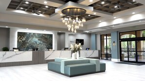 A modern reception area with a marble reception desk, a large abstract wall art piece, a seating area with a vase of flowers, and a ceiling with recessed lighting and a chandelier. - Floridays Resort Orlando (Orlando)