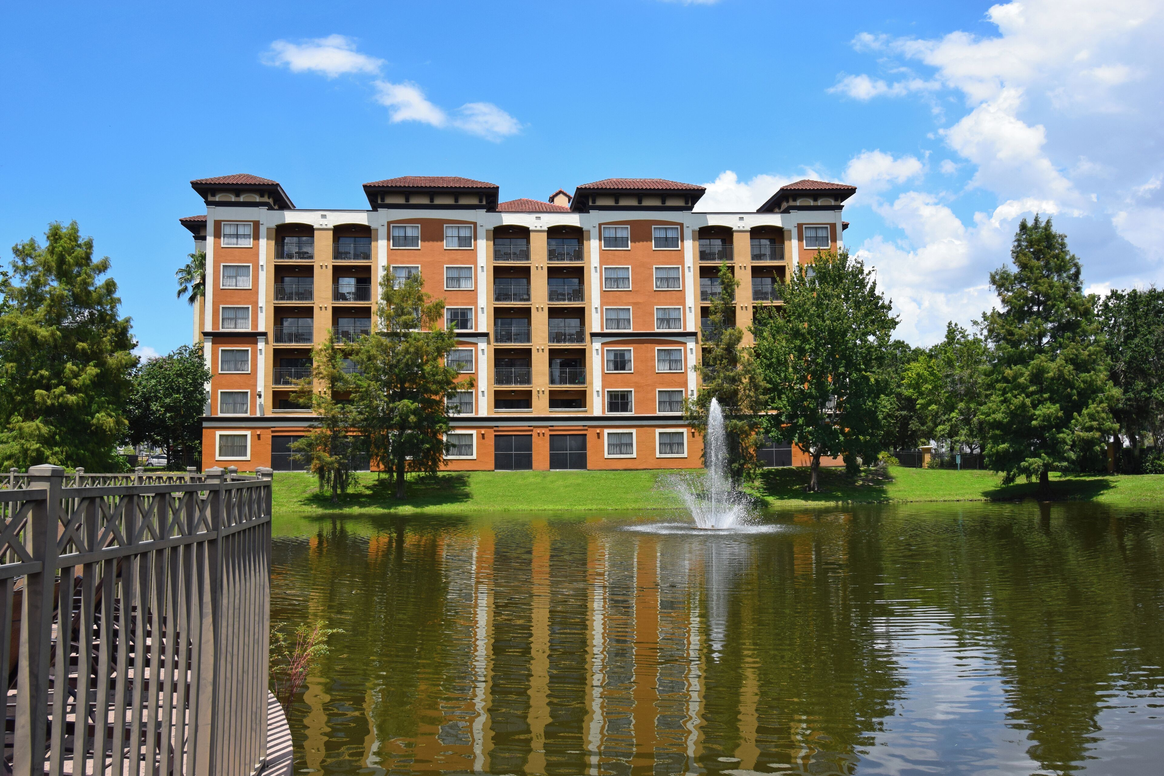 A multi-story building with a courtyard, a fountain, and a metal fence.